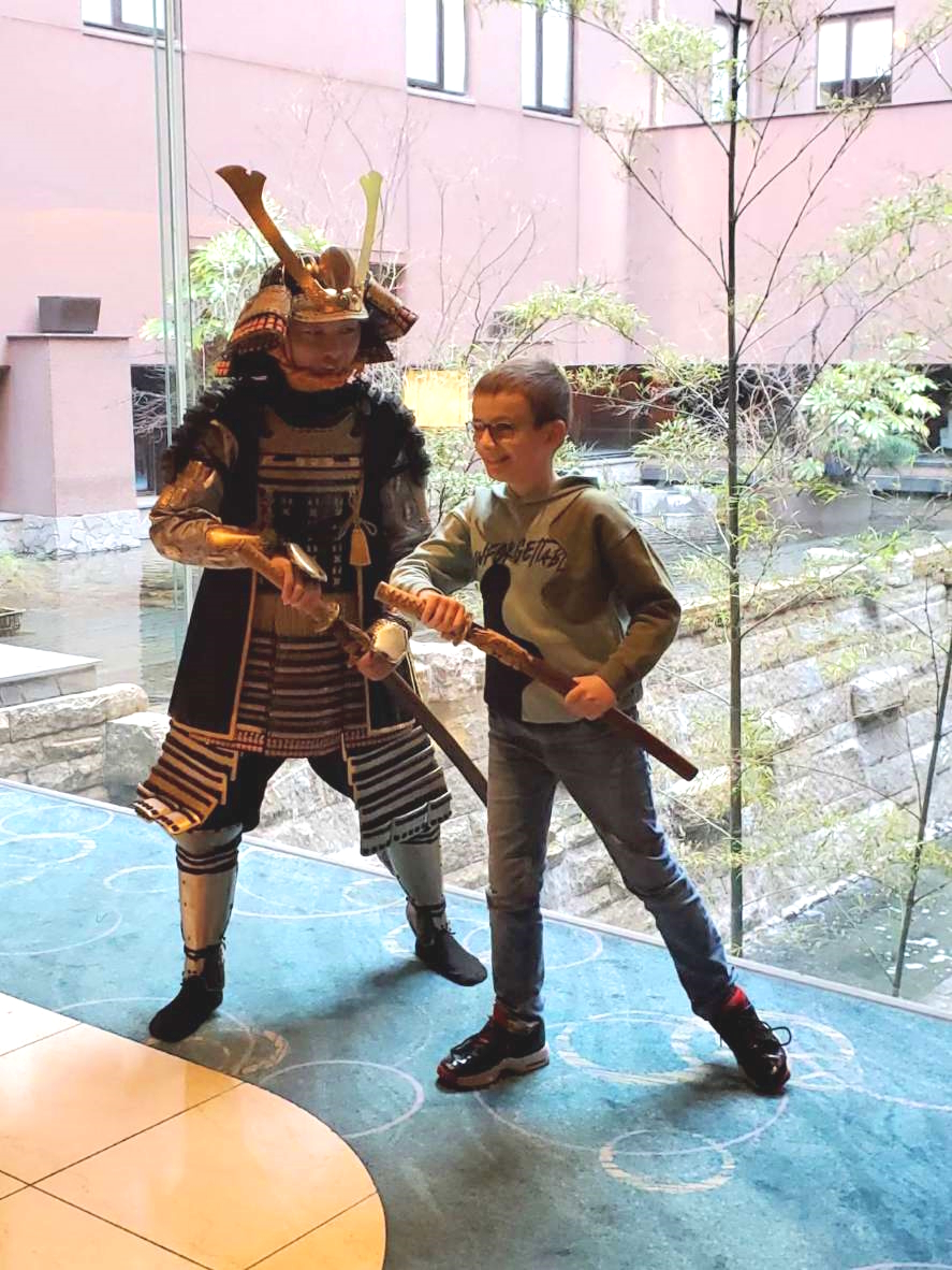 Child and samurai practicing with wooden swords by the window